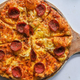 Pepperoni pizza on cutting board against a white background